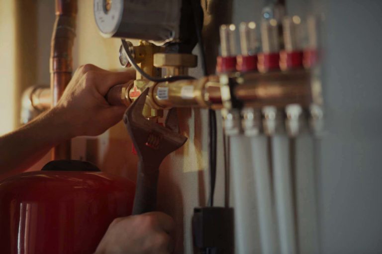 A person tightening a valve with a wrench, part of a plumbing system installation or repair, reflecting Asheville plumbing services.
